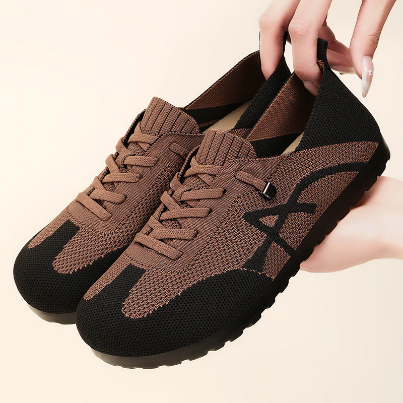 Brown and black sneakers held by a hand on a beige background