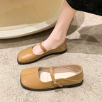Beige flat shoes with a strap on a textured surface