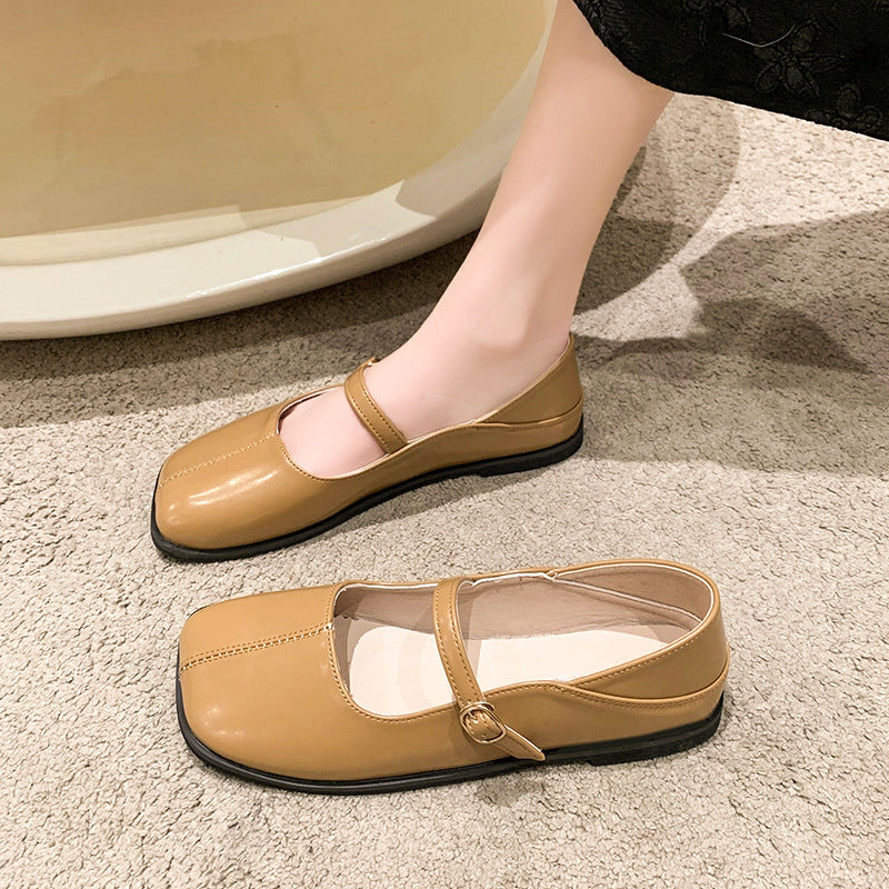 Beige flat shoes with a strap on a textured surface