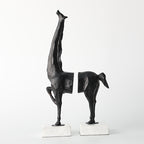 Two black abstract sculptures on white stands against a white background