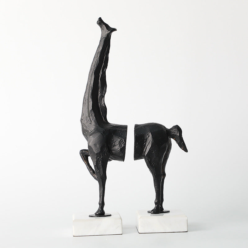 Two black abstract sculptures on white stands against a white background