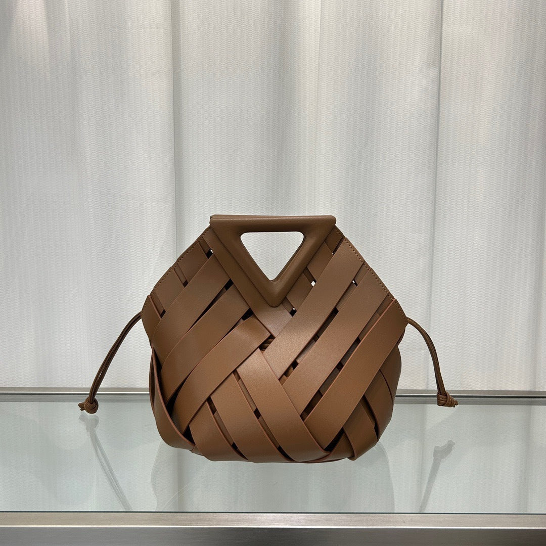 Brown  leather handbag on a reflective surface with a neutral background
