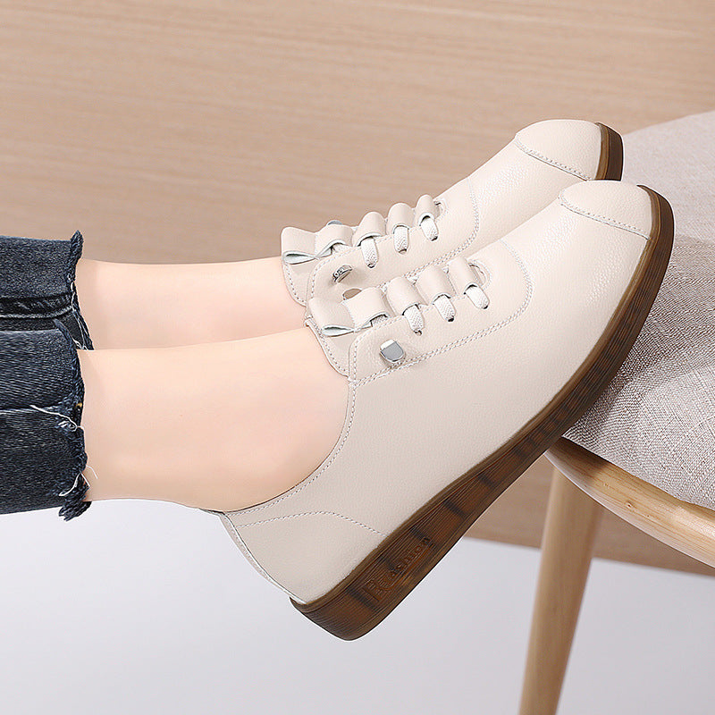 White sneakers with brown soles worn by a person sitting on a chair.