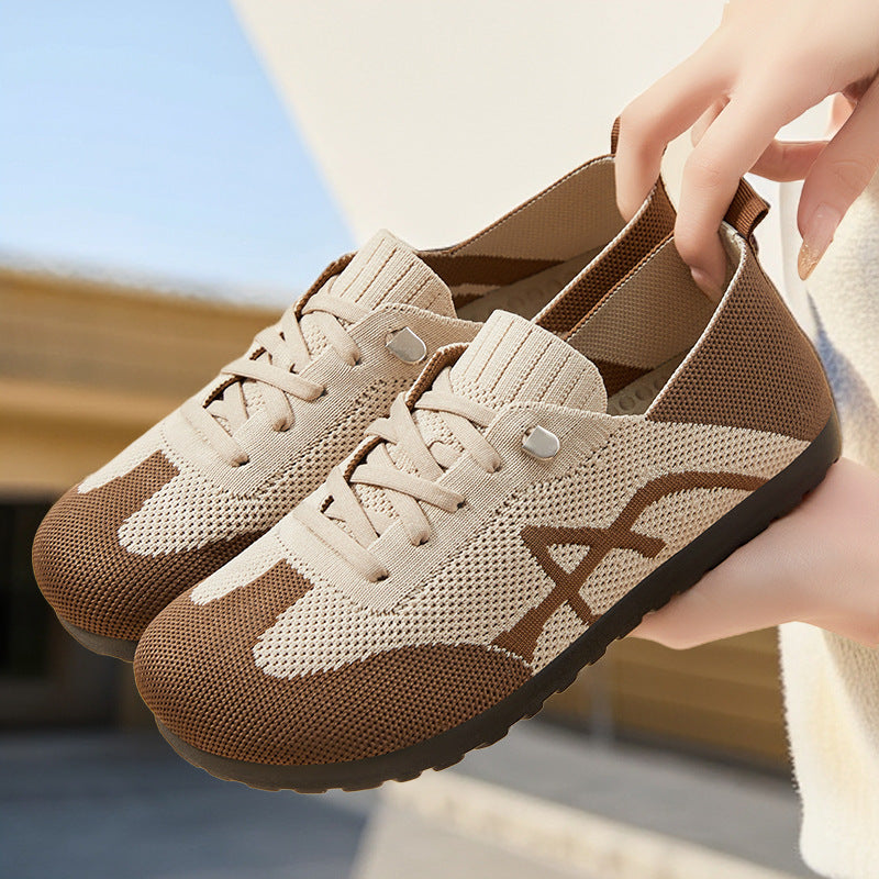 Beige and brown sneakers with a hand holding one shoe, blurred background
