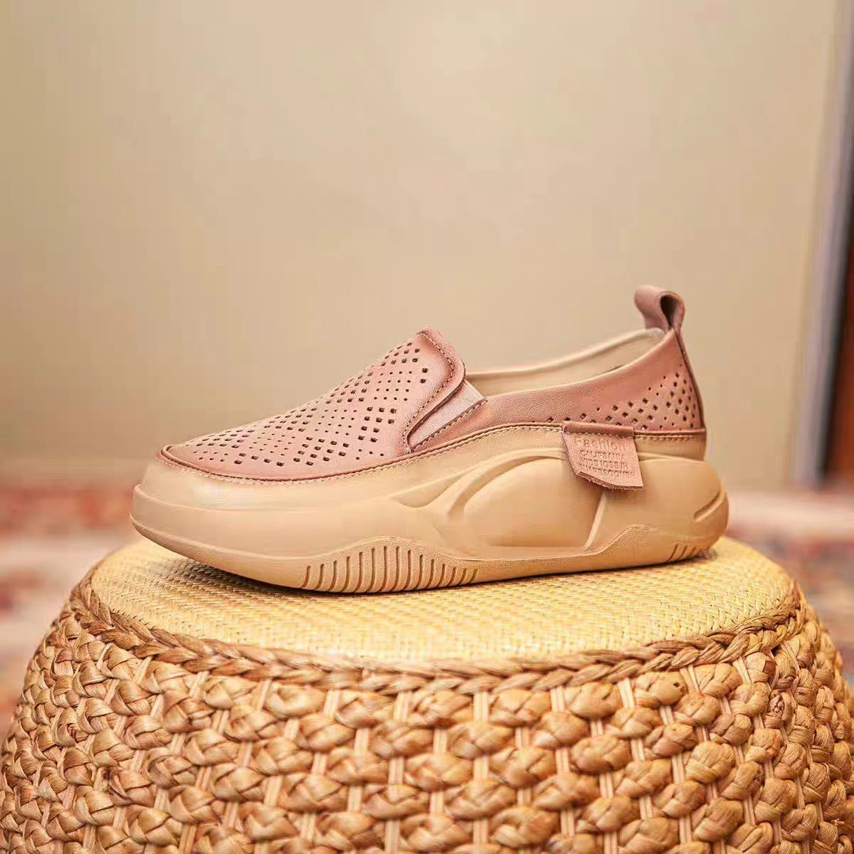 Pink and beige sneaker on a woven stool with a neutral background