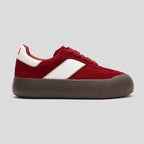 Red and white sneaker with a brown sole on a light gray background