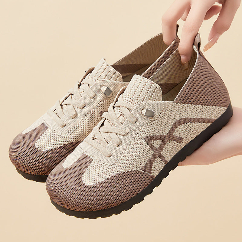 Beige and brown sneakers with a hand lifting one of them on a beige background