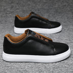 Black leather shoes with brown accents on a gray background