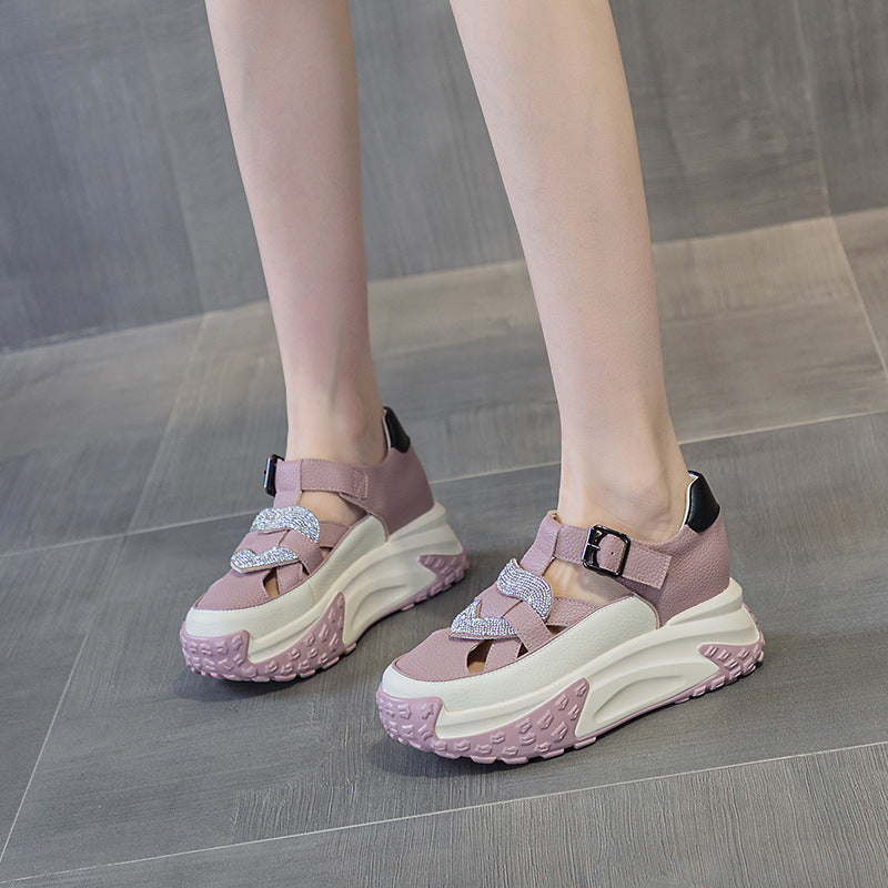 Grey  sandals worn by a person sitting on a chair with a gray background