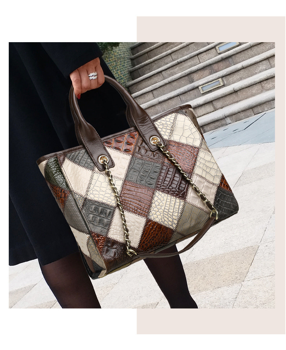 Patchwork handbag held by a person on a city street.