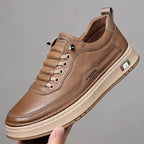 Brown leather shoe held by a hand against a gray background