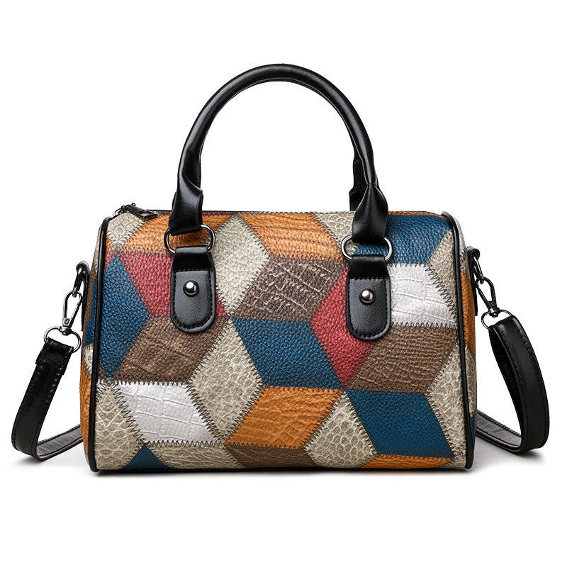Multicolored patchwork handbag with black handles and strap on a white background