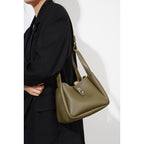 Person wearing a black outfit with a green handbag on a white background