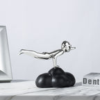 Decorative sculpture of a figure on a cloud with a laptop and box in the background