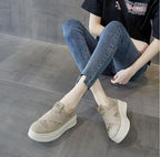 Person wearing beige slip-on shoes with white soles on a gray floor.