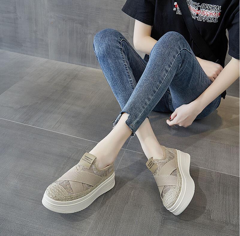 Person wearing beige slip-on shoes with white soles on a gray floor.