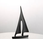 Black sailboat sculpture on a white surface with a light gray background
