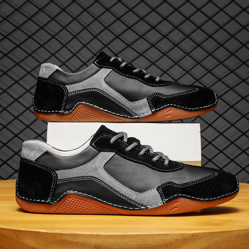Pair of black, gray, and brown sneakers on a wooden surface with a grid-patterned background.