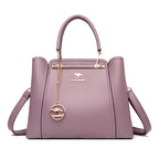 Purple handbag with a gold chain and emblem on a white background