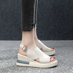 White wedge sandals worn with dark jeans on a gray floor.
