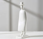 White sculpture of a figure wearing a hat on a light gray background