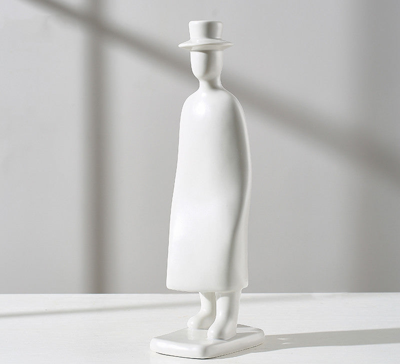 White sculpture of a figure wearing a hat on a light gray background
