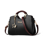 Black handbag with brown accents and a star charm on a white background