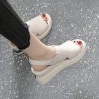White sandals worn on a gray floor