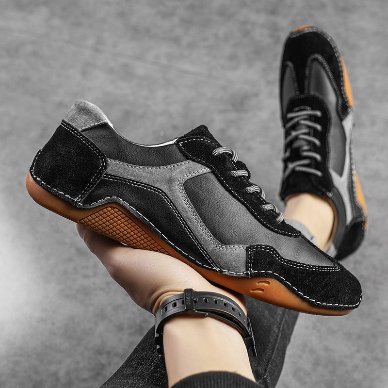 Black and gray sneakers with brown soles held by a person against a gray background