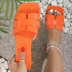 Orange sandals worn on a person's foot with a blurred natural background