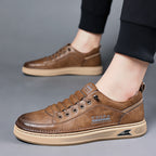 Brown leather sneakers worn by a person on a gray background