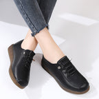 Black leather shoes with brown soles worn by a person on a white background