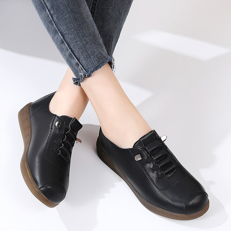 Black leather shoes with brown soles worn by a person on a white background