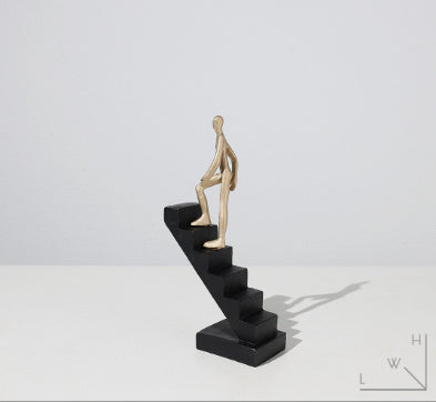 Statue of a figure climbing stairs on a white background