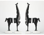 Set of four black abstract sculptures on white bases against a white background