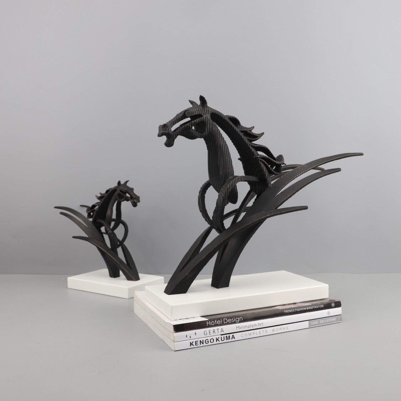 Black horse sculptures on white bases against a gray background