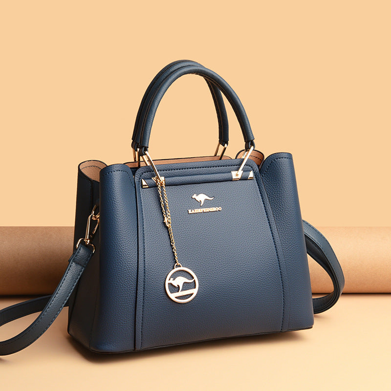 Blue handbag with a gold chain and kangaroo emblem on a beige background