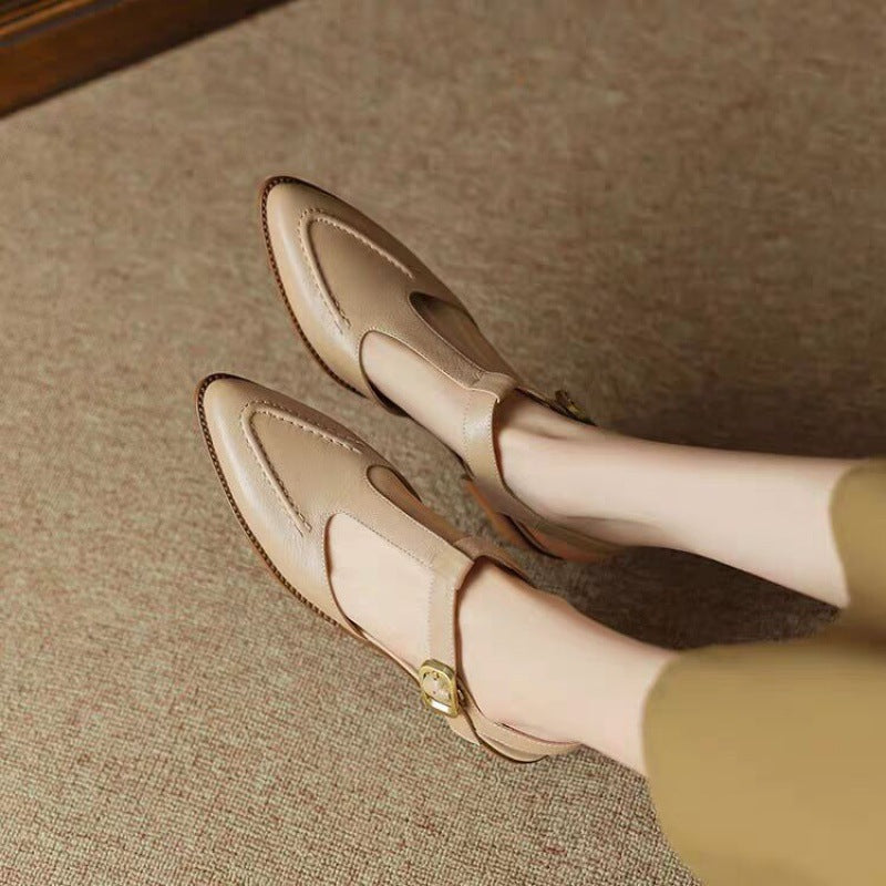 Beige loafers worn by a person on a textured surface