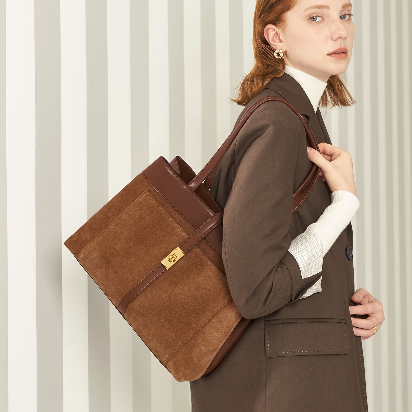 Woman holding a brown leather bag against a striped background