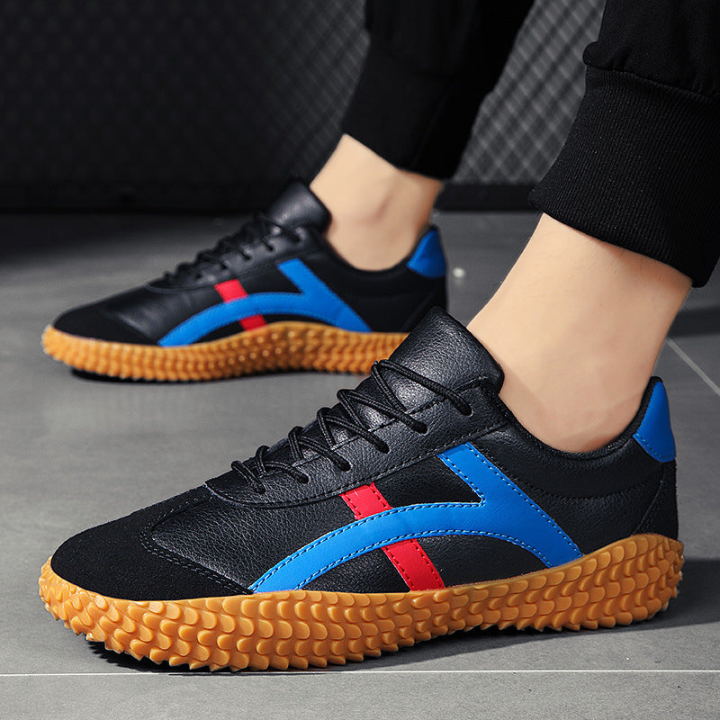 Black sneakers with blue and red accents worn by a person on a gray floor.