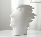White ceramic vase shaped like a stylized face on a white background