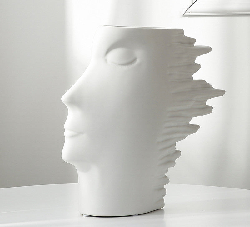 White ceramic vase shaped like a stylized face on a white background