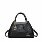 Black handbag with crocodile texture and gold chain on a white background